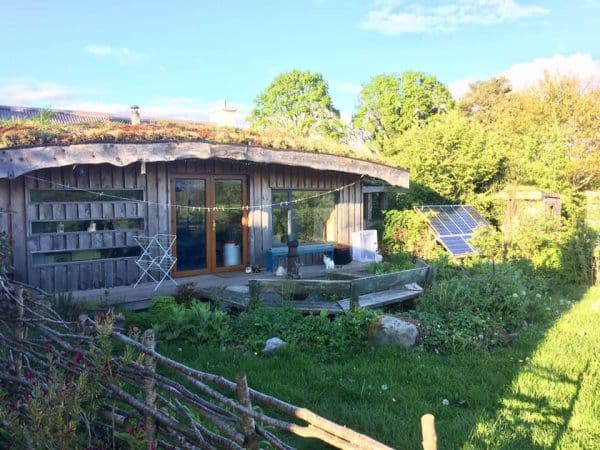 Lackan Cottage Farm - photo du cottage en bois avec toiture vegetale et à côté les panneaux photovoltaïques