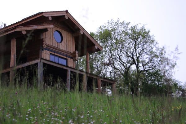 Maison en fuste prise en contre plongée depuis la prairie devant