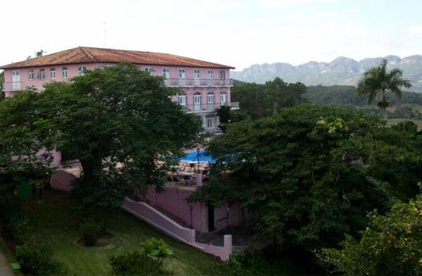 Bâtiment rose, avec piscine, entouré d'arbres