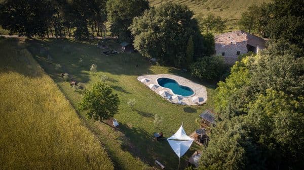 Agritourismo Sant'Egle vue du ciel avec la piscine en 8 au centre de la pelouse entourée de transat et dans le coin haut gauche la maison en pierre