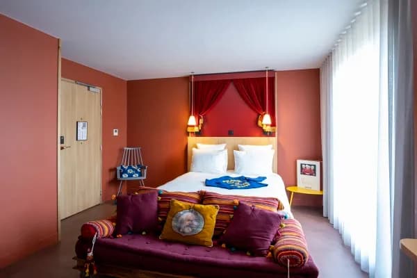 chambre rouge avec un lit double et un petit canapé