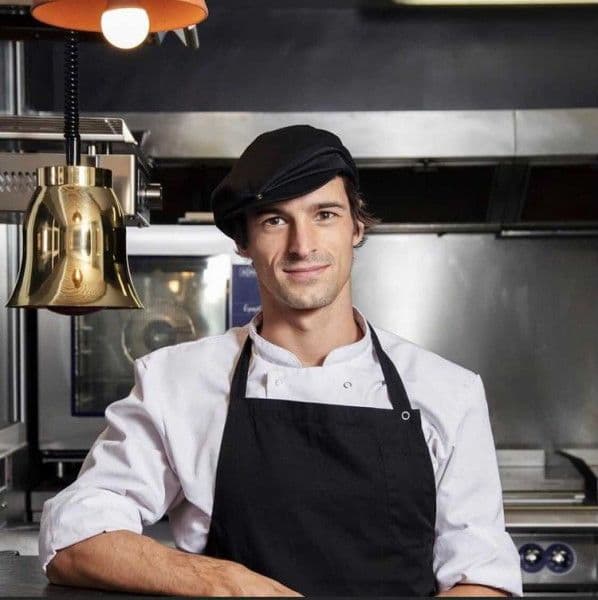 photo portrait Nicolas Bellard dans le cuisine du restaurant avec une casquette typiquement parisienne sur la tête