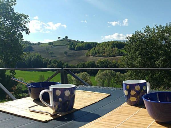 Table dressée pour le petit dejeuner sur la terrasse exterieure avec une vue dégagée sur la campagne vallonée