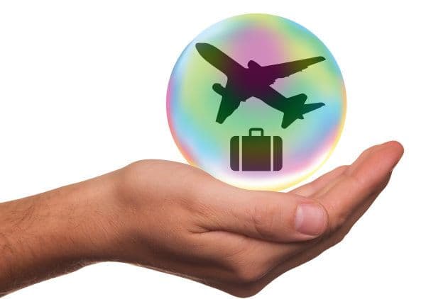 Une main horizontale qui supporte une bulle avec un avion et une valise